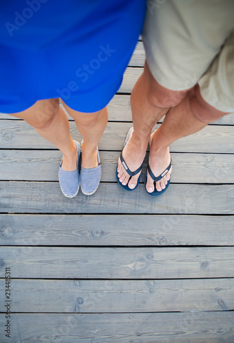 tanned guy and girl are standing on a wooden bridge.