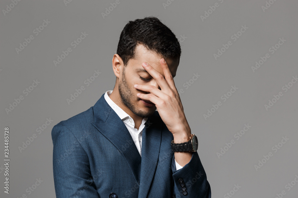 Sad tired business man with headache posing isolated over grey wall background. Sad tired business man with headache posing isolated over grey wall background.