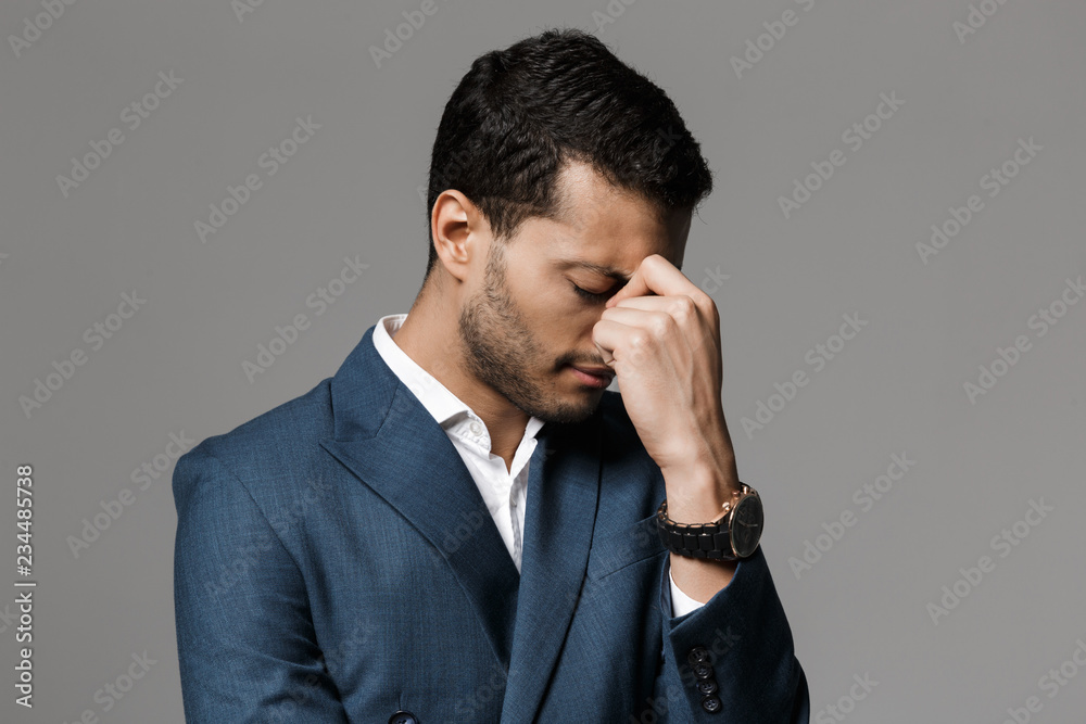 Sad tired business man with headache posing isolated over grey wall background. Sad tired business man with headache posing isolated over grey wall background.
