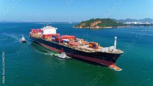 Tug boats drag container ship to sea port for unload container to container warehouse for logistics import export, shipping or transportation concept background.