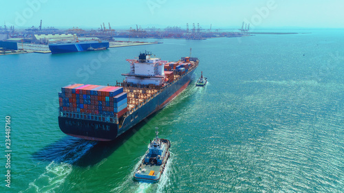 Aerial view Tug boats drag container ship to sea port for unload container to container warehouse for logistics import export, shipping or transportation concept.