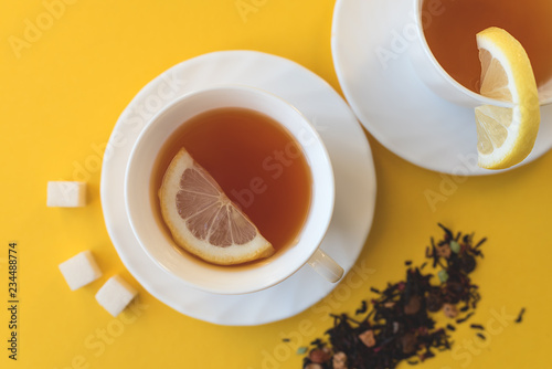 A pair of cups of tea with lemon and sugar.