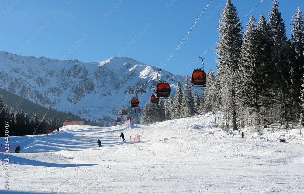 Cableway cabins and skiers on a sunny day on the slopes of the Jasna ski resort.