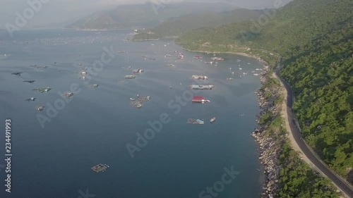 2K Aerial top view of beautiful Vietnamese landscape with curvy mountain road in the coastal seaside and . Phu Yen, Vietnam. A lot of fisherman boats in the ocean at sunrise