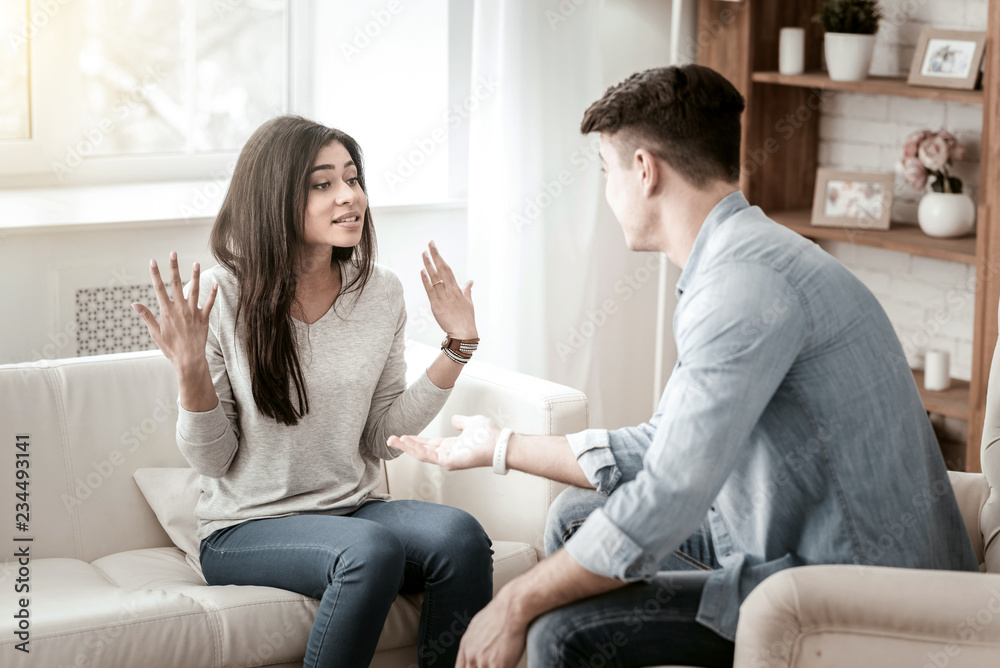 Obraz premium Our misunderstandings. Attentive male person sitting in semi position and trying to calm down his girlfriend
