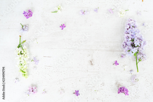 Fresh lilac flowers and twigs over white wooden background with copy space, flat lay top view floral frame