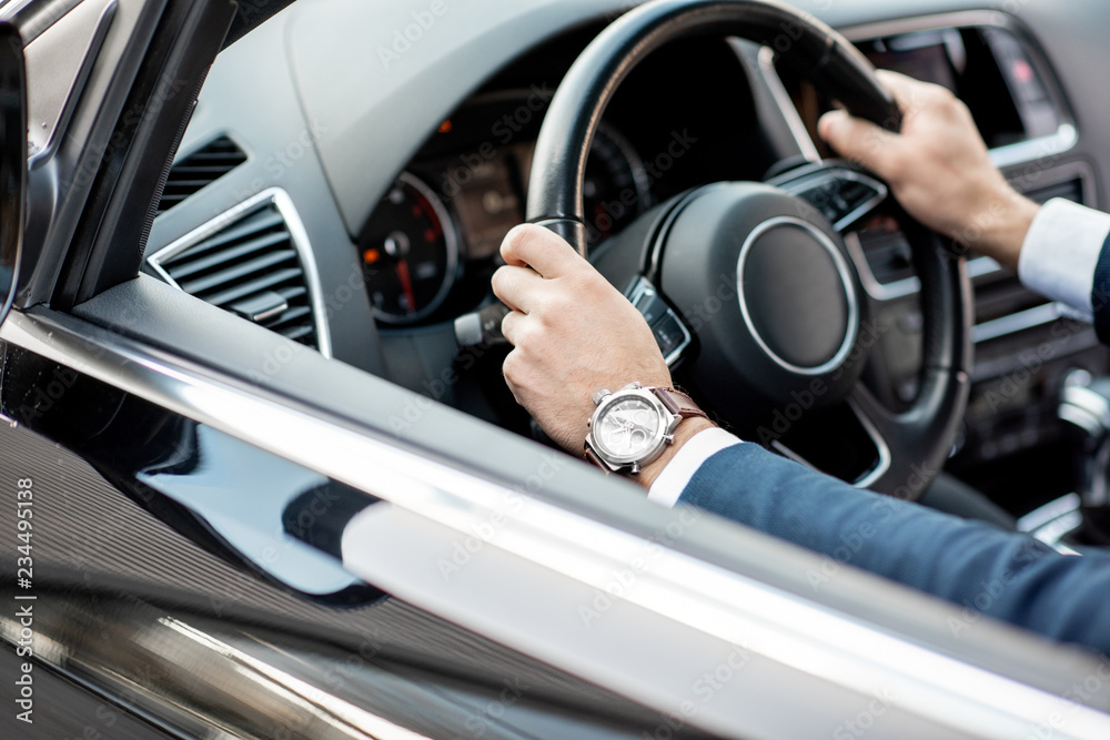 Close-up of businessman's hands on the helm of a luxury car