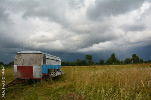 Old bus with honey bees beehives in the field with rain and stormy weather. Beehive transport. Relocating bees.