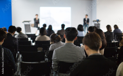 "Audience Watching a Presentation. Blurred Presenters at Conference Meeting Event. Executive Manager Speaker on Stage at Tech Business Seminar. Lecturers Presenting Training Material During Speech." © Right 3