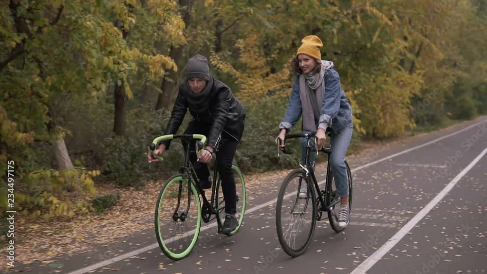Two bicycle. Couple on bikes. Romantic biking in the autumn city park. Man and woman riding bikes. Active friends leisure. Slow motion Two bicycle. Couple on bikes. Romantic biking in the autumn city park. Man and woman riding bikes. Active friends leisure. Slow motion