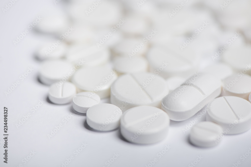 Close up view of heap of white pills with blurred white background Close up view of heap of white pills with blurred white background