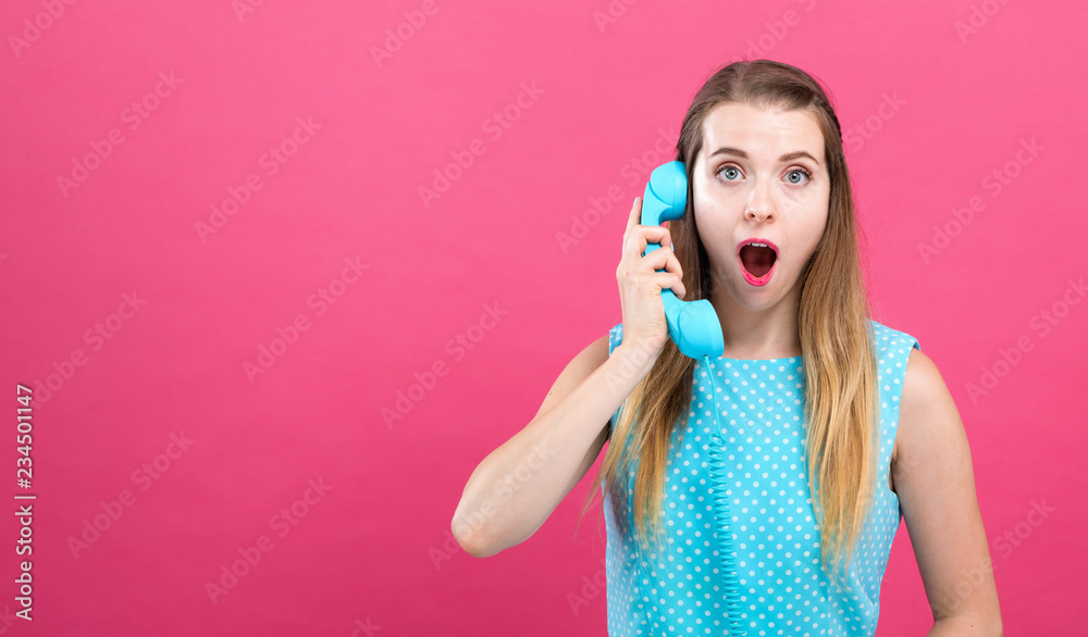 Young woman talking on an old fashioned retro phone on a pink background Young woman talking on an old fashioned retro phone on a pink background