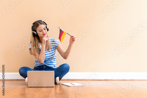 Young woman with Germany flag using a laptop computer against a big interior wall photo