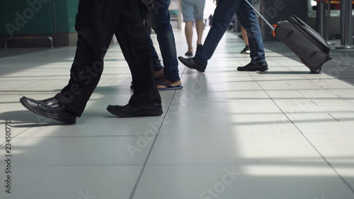 Close up of feet of unrecognizable people with baggages walking in terminal airport