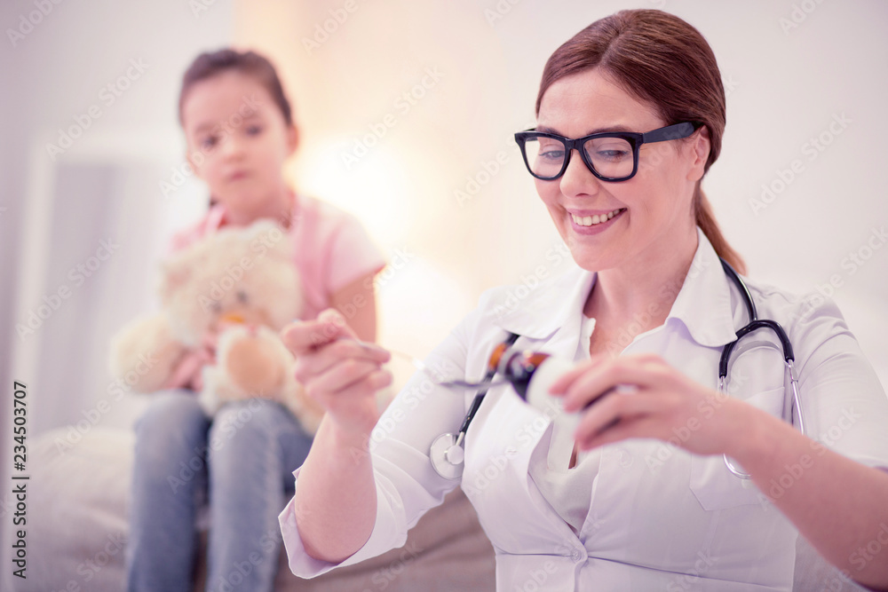 Doctor game. Cute little dark-haired girl playing doctor game examining her toy sitting on sofa at home Doctor game. Cute little dark-haired girl playing doctor game examining her toy sitting on sofa at home