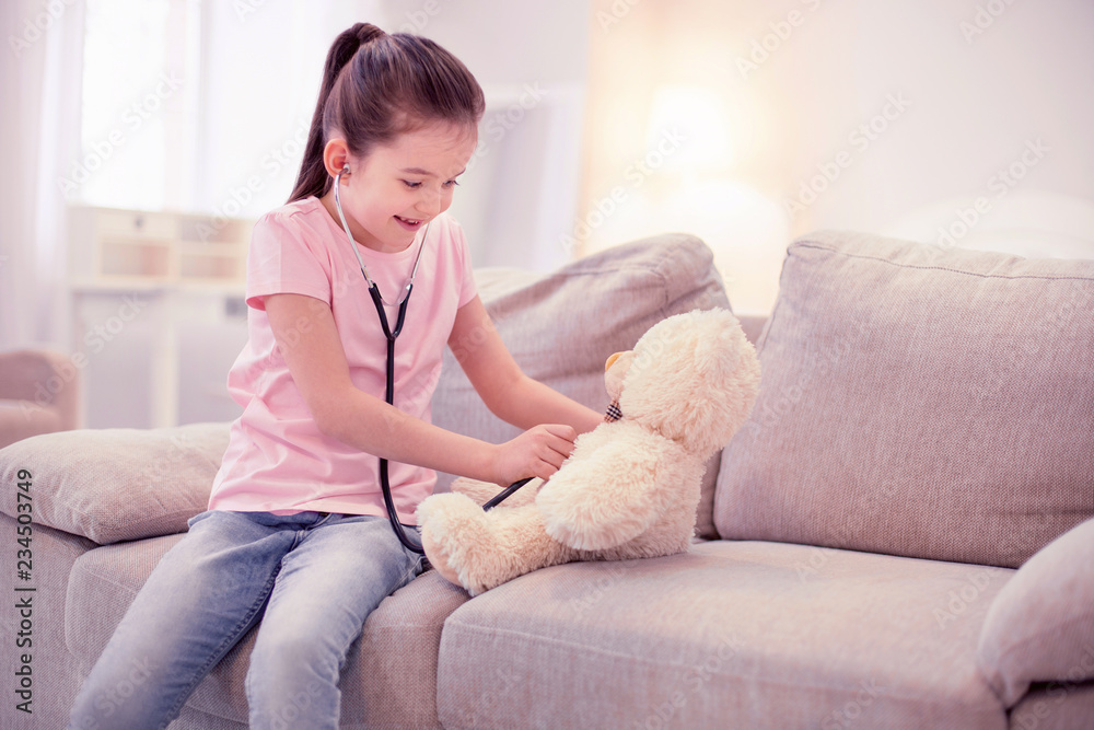 Play with bear. Cute little girl pretending to be a doctor playing with her teddy bear in the living room Play with bear. Cute little girl pretending to be a doctor playing with her teddy bear in the living room