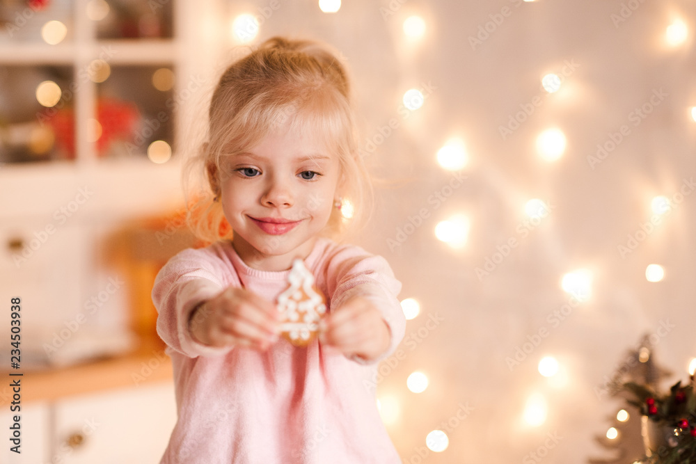 Smiling baby girlholding gingerbread cookie closeup. Winter holidays. Christmas season.