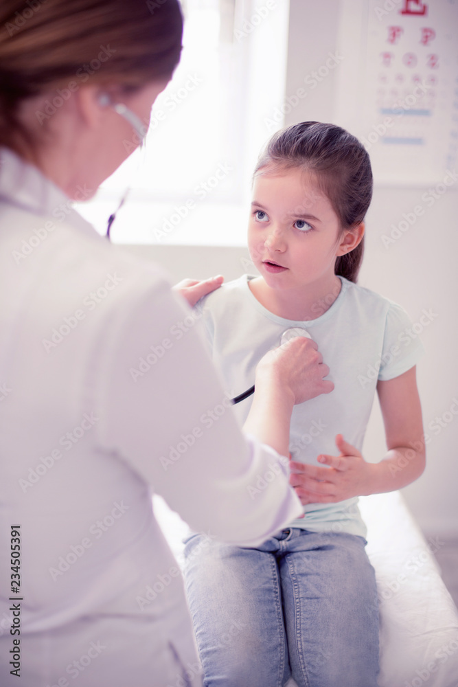 Preschool girl. Cute dark-haired preschool girl wearing jeans visiting experienced family physician Preschool girl. Cute dark-haired preschool girl wearing jeans visiting experienced family physician