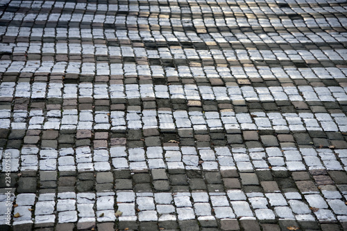 Detail of zebra striped pedestrian walk on cobblestone street.