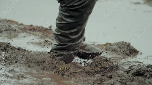 Man walks through the mud in rubber boots