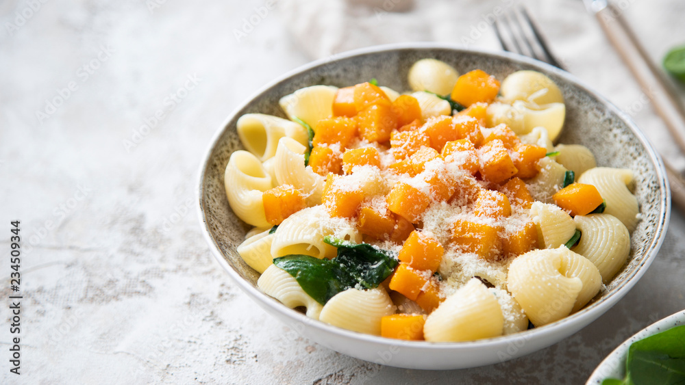 Pasta with pumpkin, spinach and cheese on shabby grey background. Pasta with pumpkin, spinach and cheese on shabby grey background.