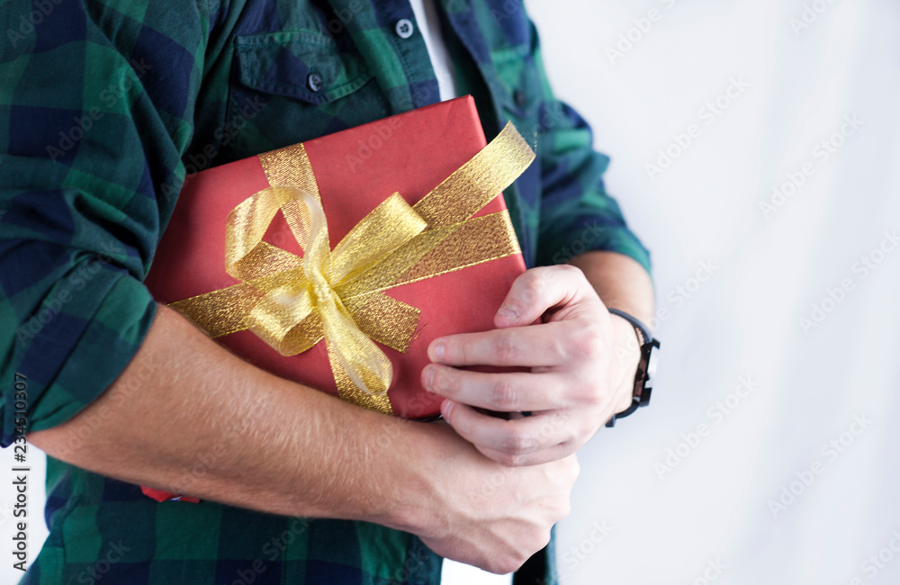 Young handsome guy holds a gift in his hands close-up