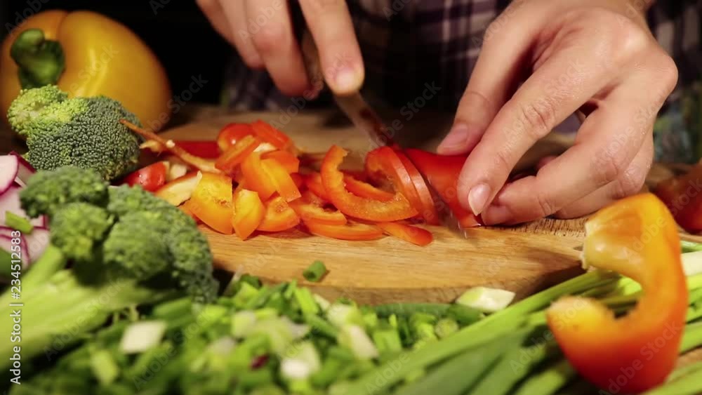 Woman hands slicing sweet Red Bell Pepper on a wooden cutting board. Healthy food concept.