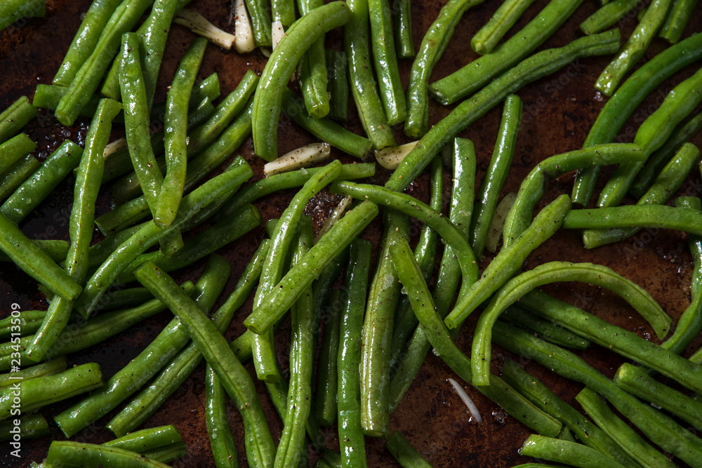 Close up of green beans with sliced garlic on a baking sheet Close up of green beans with sliced garlic on a baking sheet