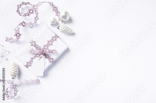 Christmas present wrapped in white paper and decorated with pink Christmas ribbon.  Flatlay. Copy space. White background