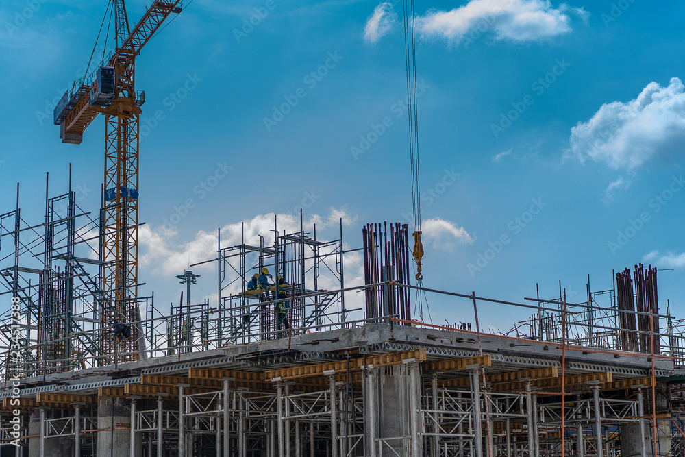 Construction Laborers working in construction site with cranes on the blue sky background. industrial building concept. Construction Laborers working in construction site with cranes on the blue sky background. industrial building concept.