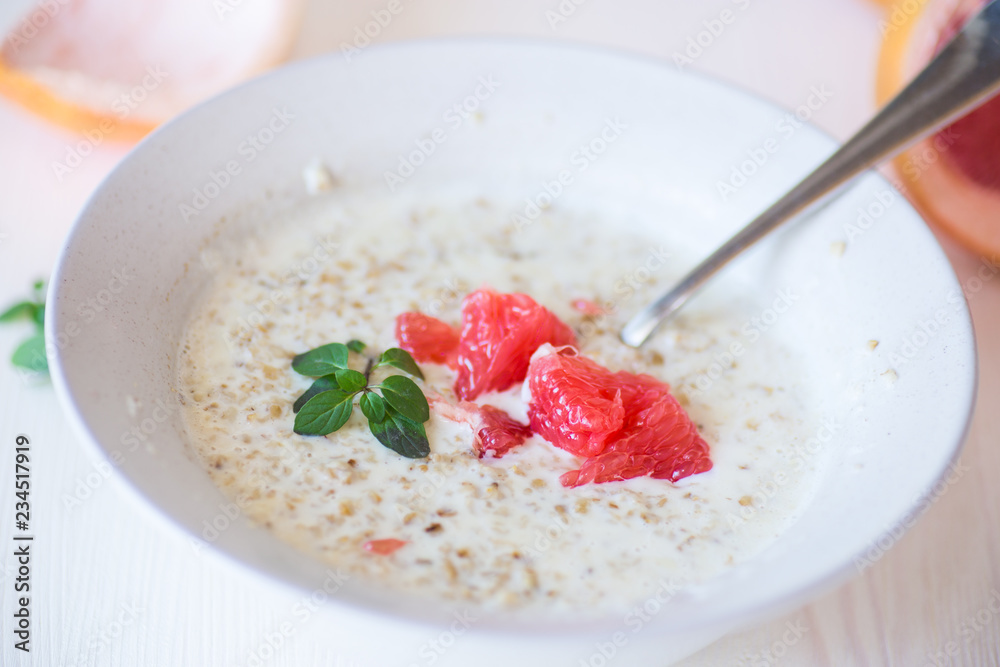 sweet oatmeal with slices of red grapefruit in a ceramic bowl sweet oatmeal with slices of red grapefruit in a ceramic bowl