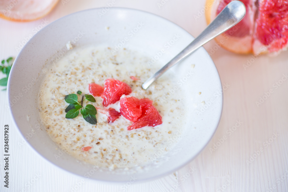 sweet oatmeal with slices of red grapefruit in a ceramic bowl