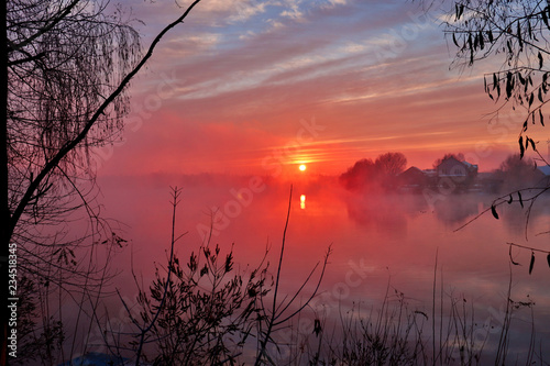 Fototapeta Naklejka Na Ścianę i Meble -  Beautiful landscape with orange sunraise at the foggy lake