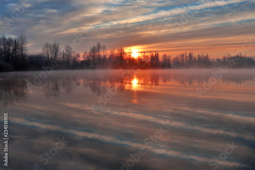 Amazing view at autumn sunrise at the foggy lake