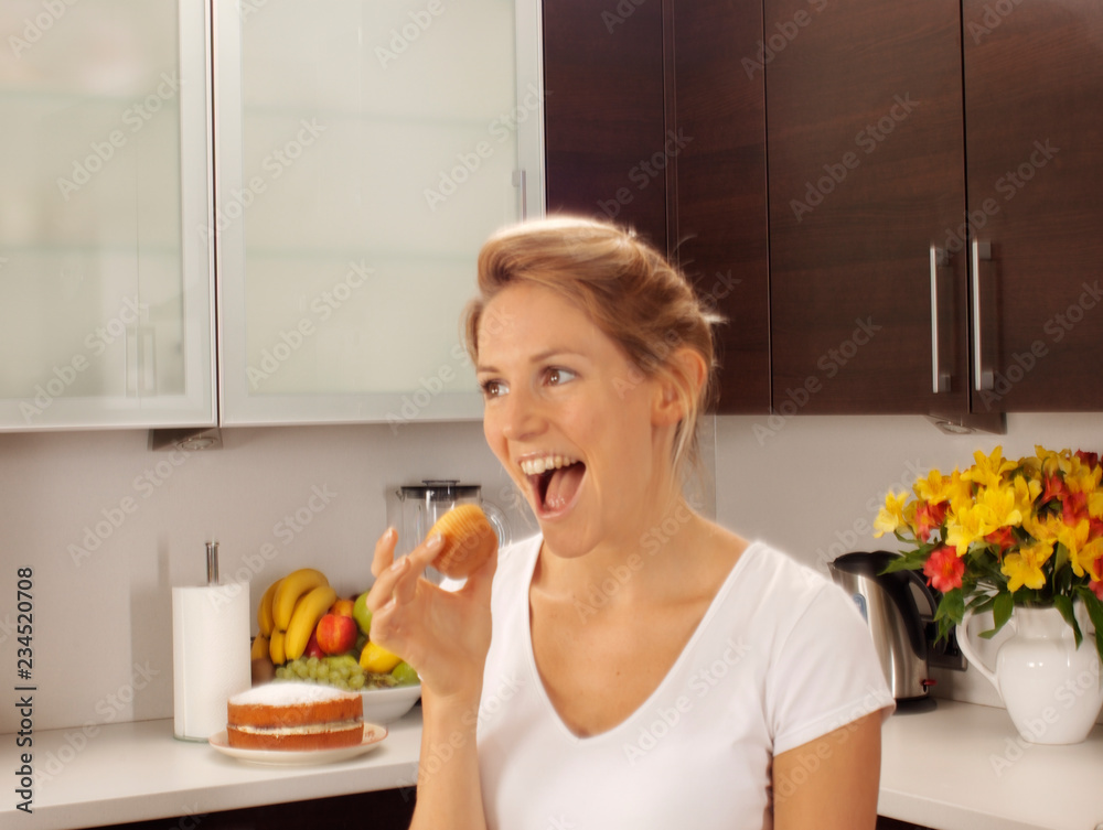 WOMAN IN KITCHEN EATING FAIRY CAKE / CUPCAKE