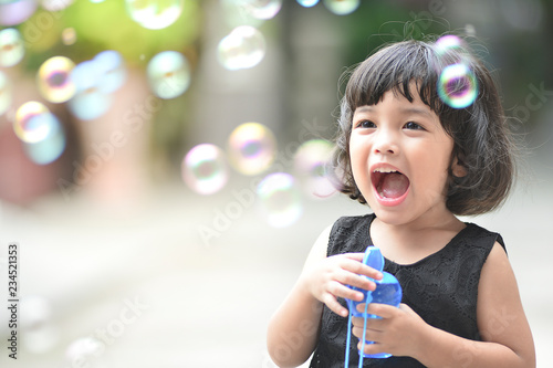 Asian little cute girl or kid blow,play air soap bubbles with smile. happiness,fun and childhood concept.