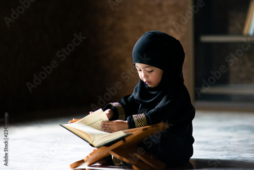 Asian Indonesian Muslim kid is reading the Quran. The Quran is indicated as the guided book for all Muslim and it is direction  to be on the heaven of God.Mosque,Islam,religion and knowledge concept.
