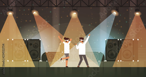 dancers couple wearing virtual reality glasses dancing on stage with light effects disco studio musical equipment multimedia speaker background flat horizontal