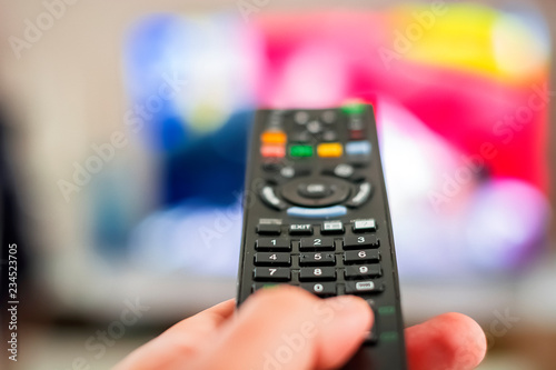 A hand pressing a television remote control button