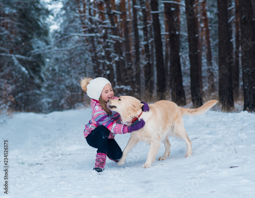 young girl playing with golden retriever on winter walk.