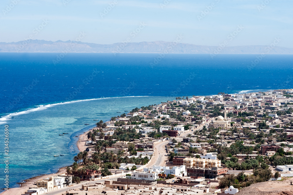 View from height on Dahab beach and coral reef. Blue sea with surf line.