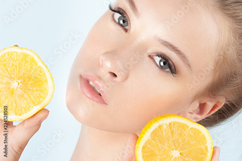 Young beautiful girl with clean perfect skin with lemon close-up