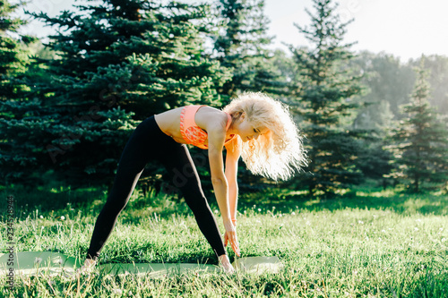 Photo of young curly-haired sports woman practicing yoga on rug  photo