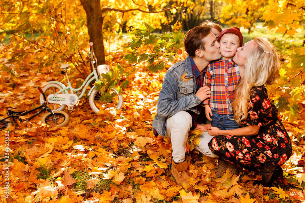 Photo of kissing parents and children sitting in autumn park Photo of kissing parents and children sitting in autumn park
