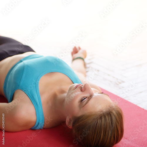 Young Caucasian woman laying in relaxing yoga pose on a mat in the class