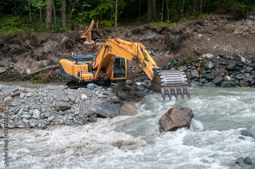 Excavator strengthens the bed of a mountain river.