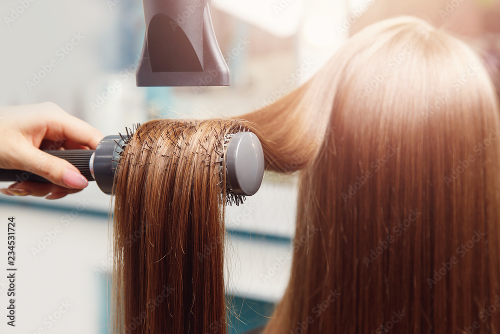 Fototapeta premium Hand of master girl in beauty salon makes drying and styling