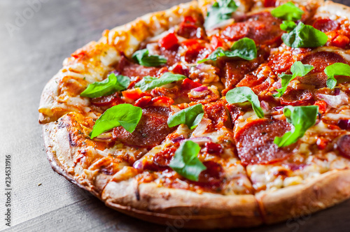 sliced Pepperoni Pizza with Mozzarella cheese, salami, chorizo, tomato sauce, pepper, Spices and Fresh arugula. Italian pizza on wooden table background
