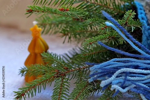 The Christmas tree is wrapped in a blue scarf with a wax candle and wheat grains on a white background. Happy New Year and Merry Christmas. Christmas concept © yuliia.terliuk