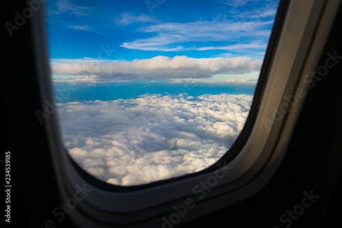 Aerial view from airplane window. Aircraft flying above land with beautiful clouds in the blue sky background. Aviation concept. Tourism,Journey,Travel concept.
